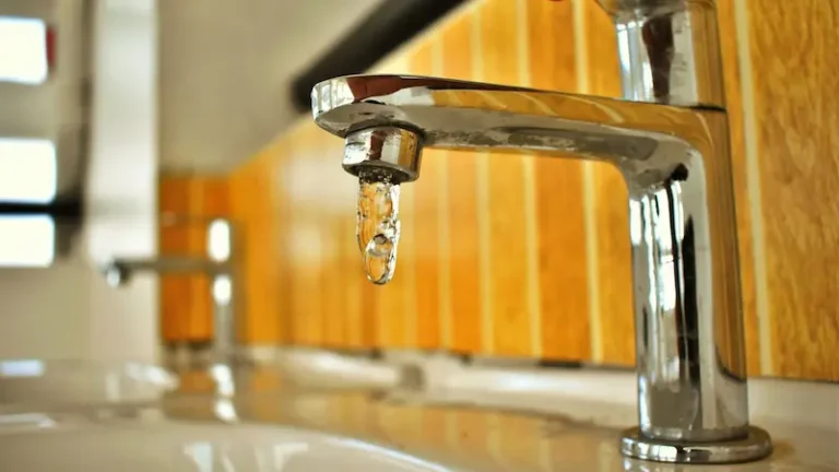 Close-up shot of a chrome faucet with a droplet of water, highlighting its sleek design.