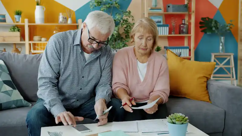Retired couple reviewing household bills and financial documents