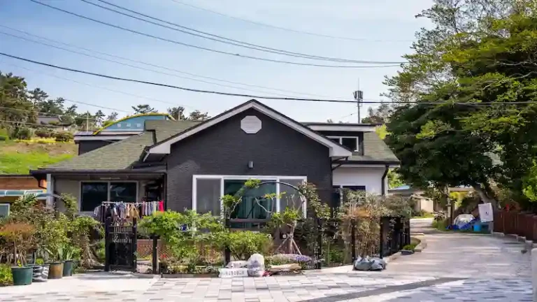 A charming suburban house with a lush front garden and laundry hanging outside on a sunny day.